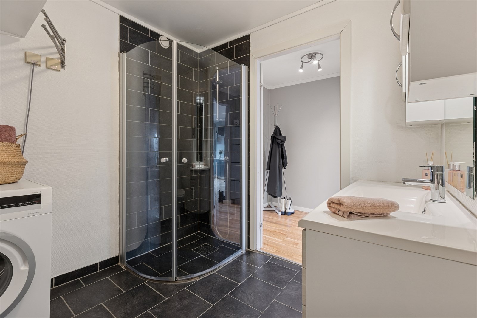 Badet har dusjhjørne med glassvegger og opplegg for vaskemaskin. Galleribilde