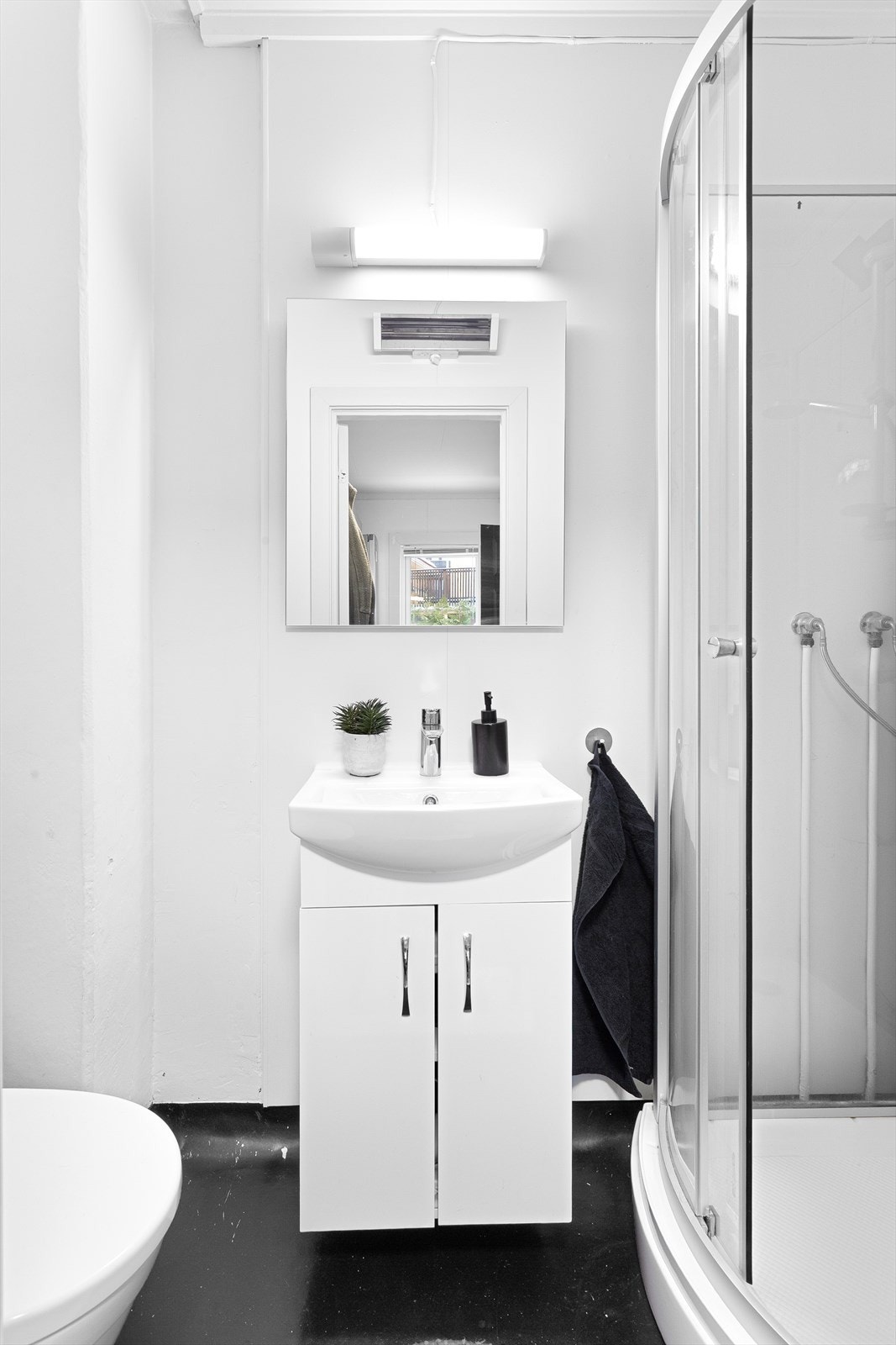 Badet er utstyrt med dusjkabinett, servant med underskap og gulvstående toalett. Galleribilde