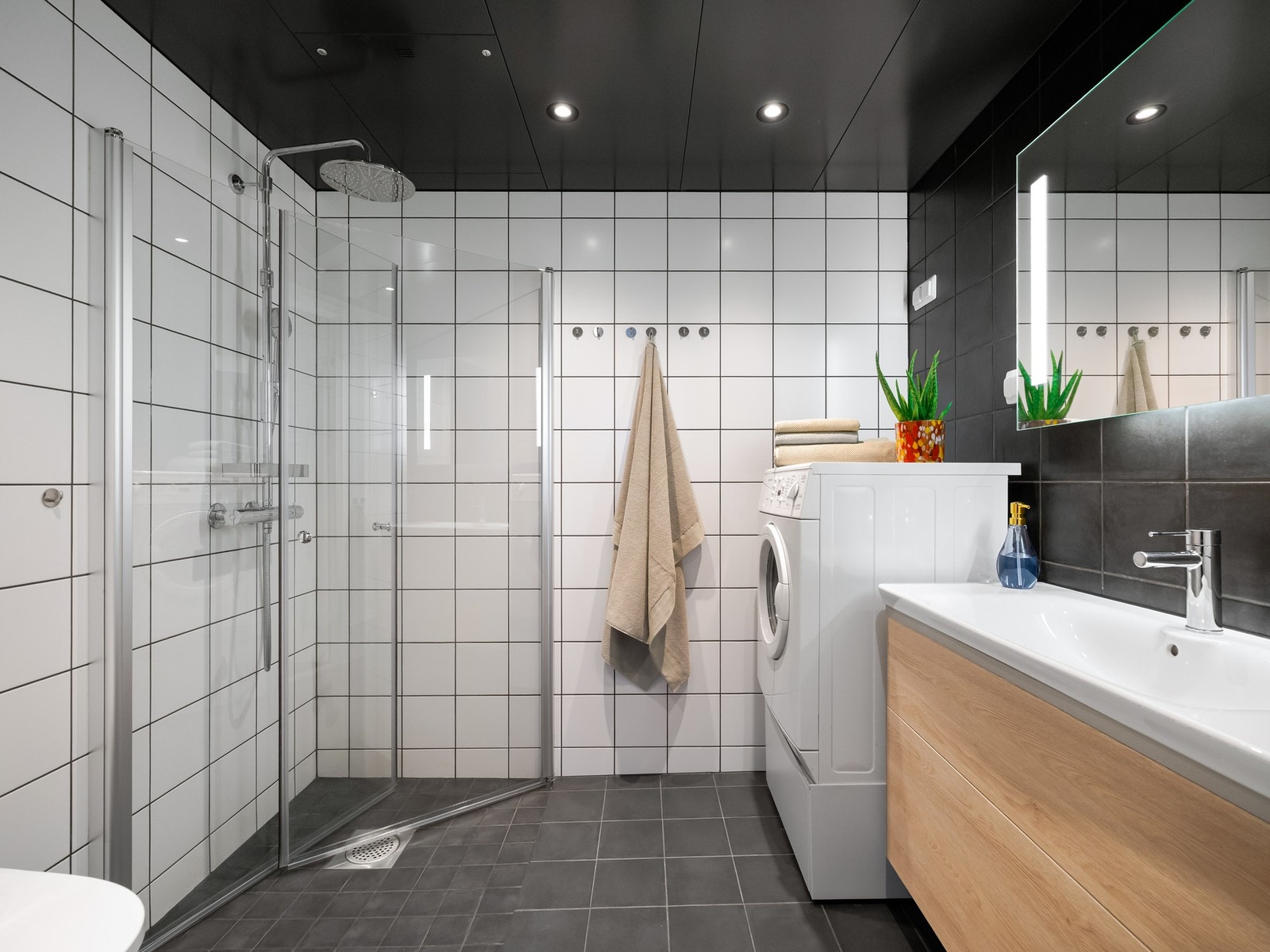 Badet er pent flislagt og fra byggeår 2022. Det er innredet med dusjsone med innfellbare glassdører, vegghengt toalett, servantskap med oppbevaring og speilskap på vegg. Galleribilde