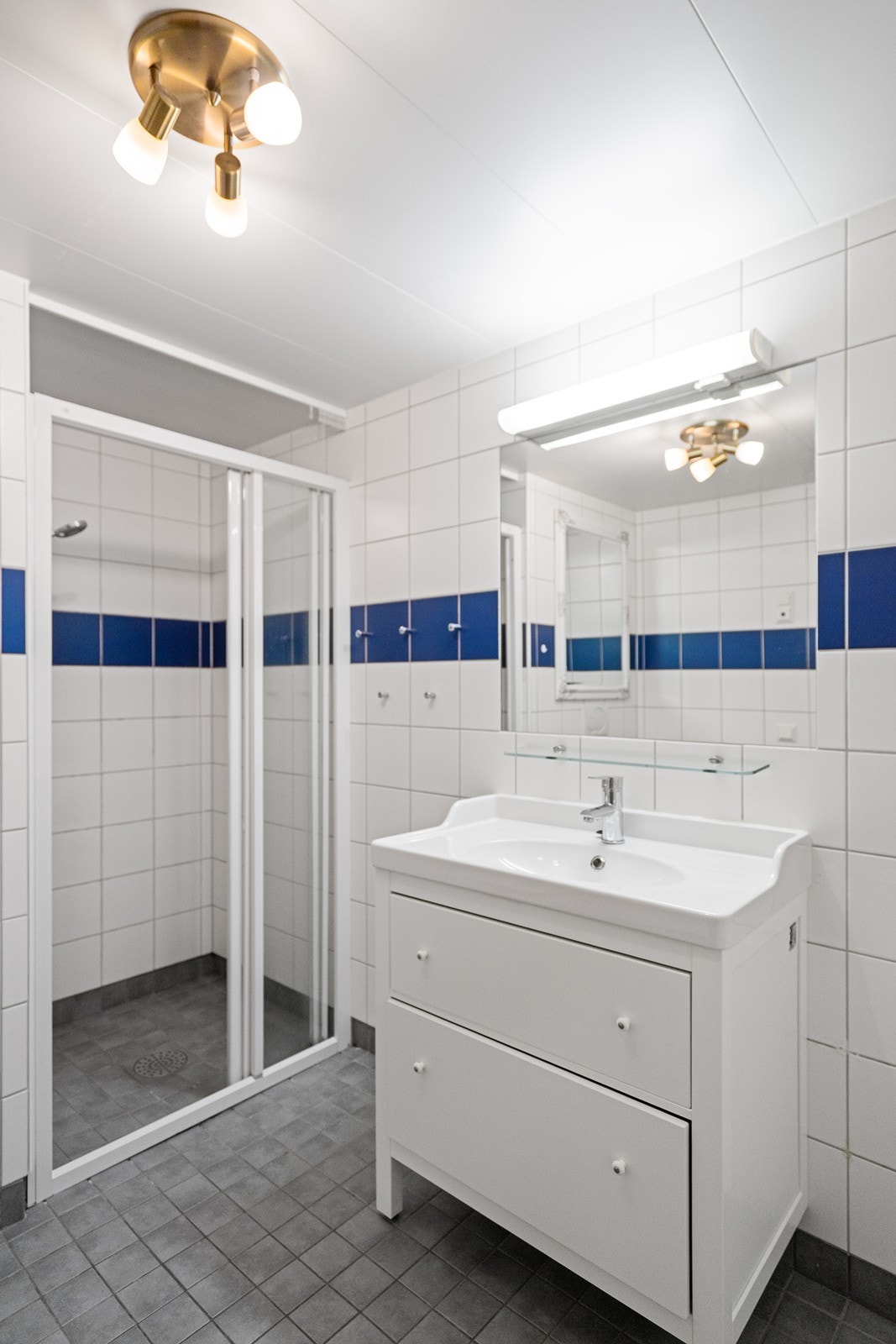 Badet er innredet med vask/underskap med speil, vegghengt toalett og dusjsone med fliser. Galleribilde