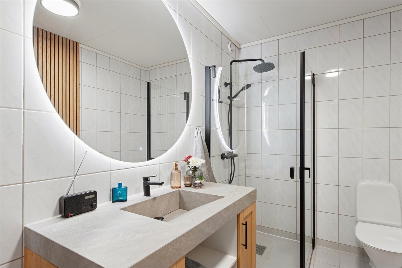 Lyst og flislagt baderom med innredningen bestående av moderne servantskap med ettgreps blandebatteri. Galleribilde