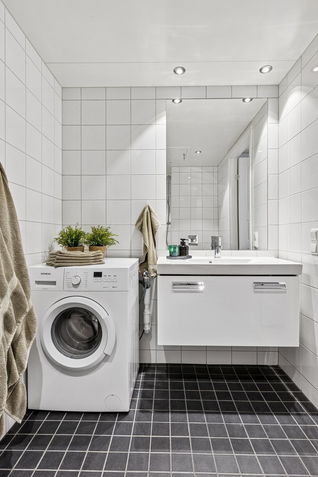 Badet i hovedetasjen er flislagt med mørke fliser på gulvet og lyse på veggene. Plass til opplegg for vaskemaskin. Galleribilde