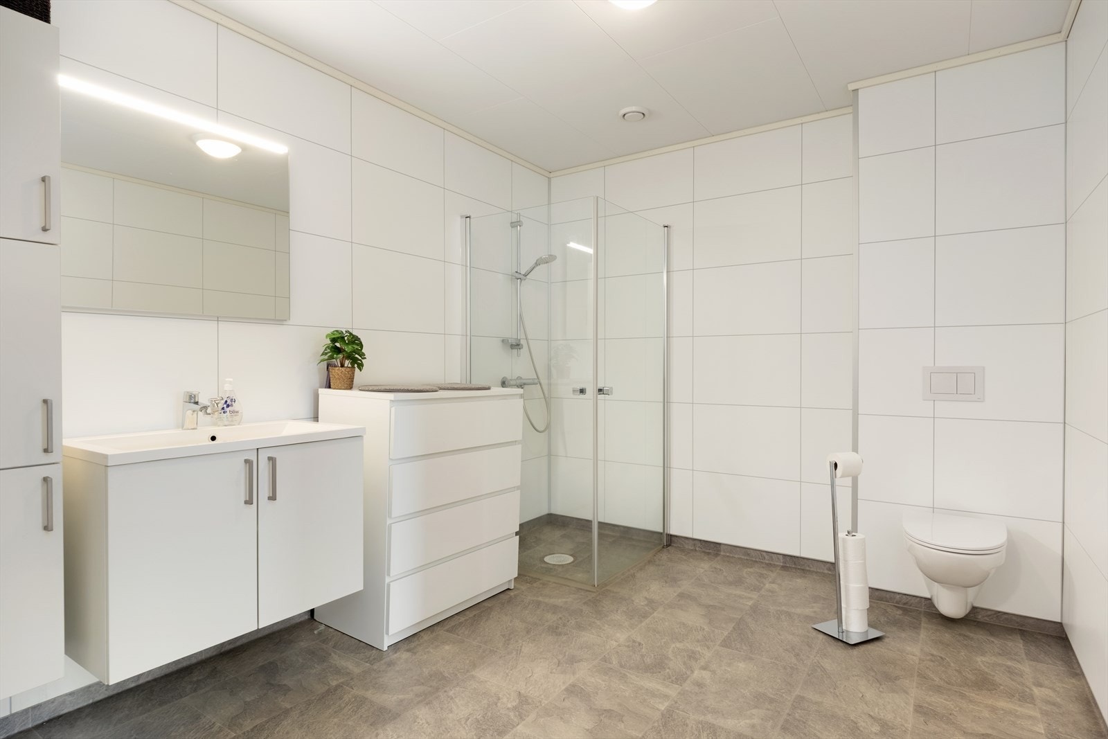 Lyst og pent bad i nøytral utførelse. Baderomsplater på vegger og belegg m/varmekablar på golv. Galleribilde