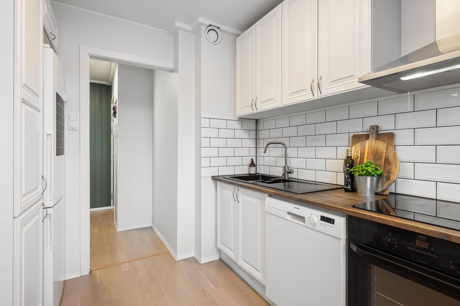 Kjøkkeninnredningen har profilerte fronter og en solid benkeplate i heltre. Fliser over benkeplaten. Galleribilde