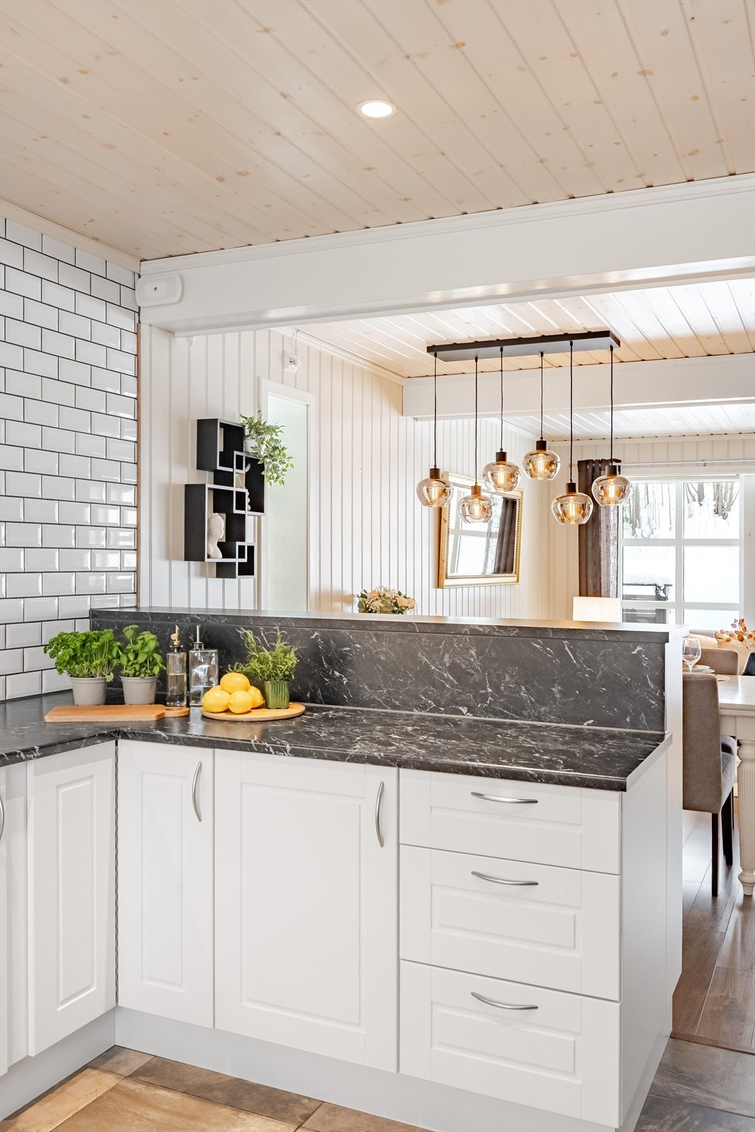 Halvøyen mot spisestuen har en praktisk løsning som skjuler kjøkkenets innhold uten å stenge rommet. Galleribilde