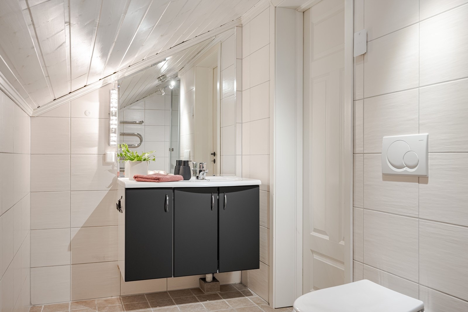 I tilknytning til soverommene i 2. etasje er det et lyst flislagt baderom fra byggeåret 2006. Moderne baderomsinnredning med sorte glatte fronter og heldekkende servant med stort tilpasset speil over. Galleribilde