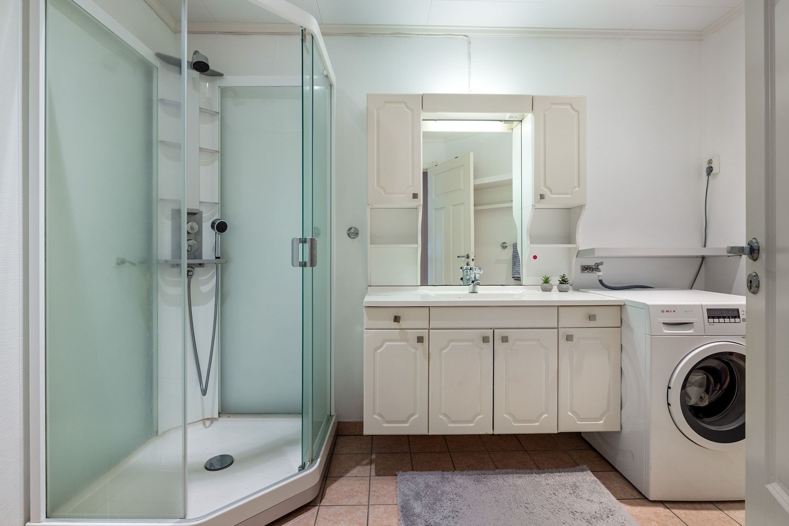 Romslig bad med flislagt gulv med varmekabler. På veggene er det baderomstapet. Galleribilde