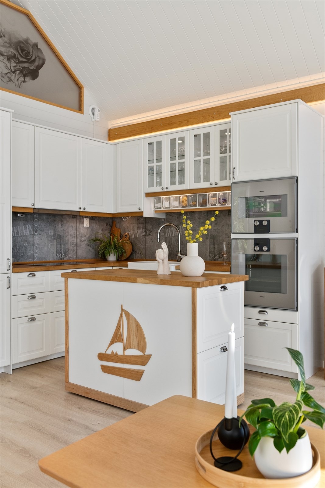 Ikea kjøkkeninnredning med hvite profilerte fronter og benkeplate av tre med nedfelt oppvaskkum med ett-greps kjøkkenarmatur. Galleribilde