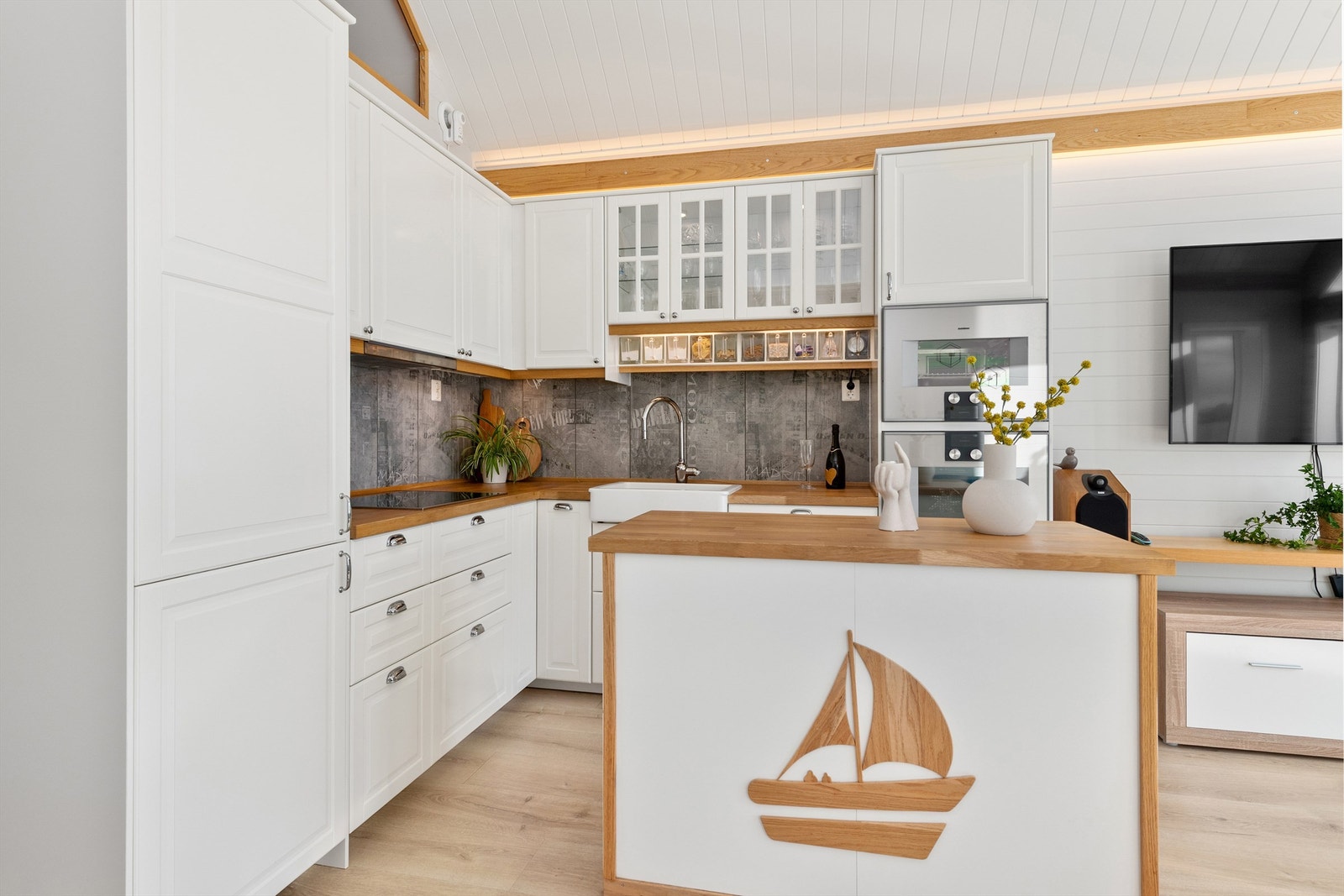 Flott kjøkkeninnredning fra Ikea med hvite profilerte fronter og benkeplate av tre med nedfelt oppvaskkum med ett-greps kjøkkenarmatur. Galleribilde