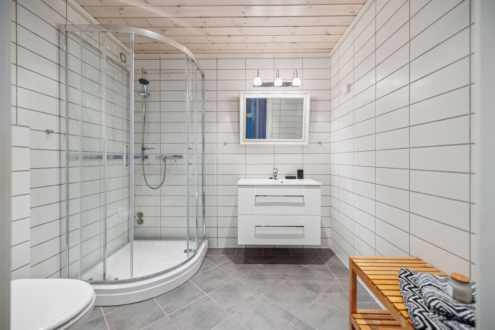 Et av hyttas to baderom innredet med servantmøbel, dusjkabinett og vegghengt toalett. Galleribilde