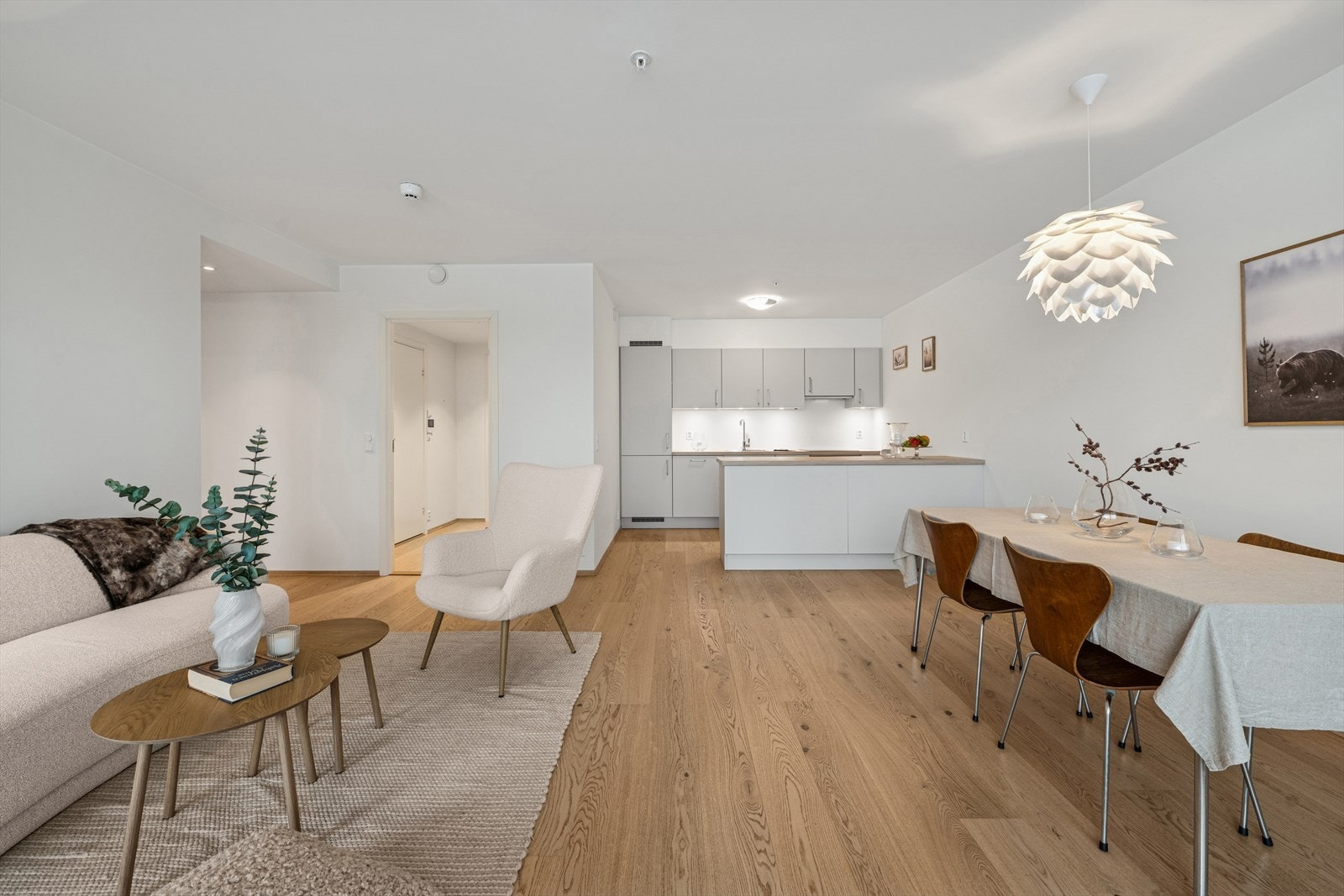 Den åpne løsningen skaper en lys og sosial sone som binder stue og kjøkken sammen. Galleribilde