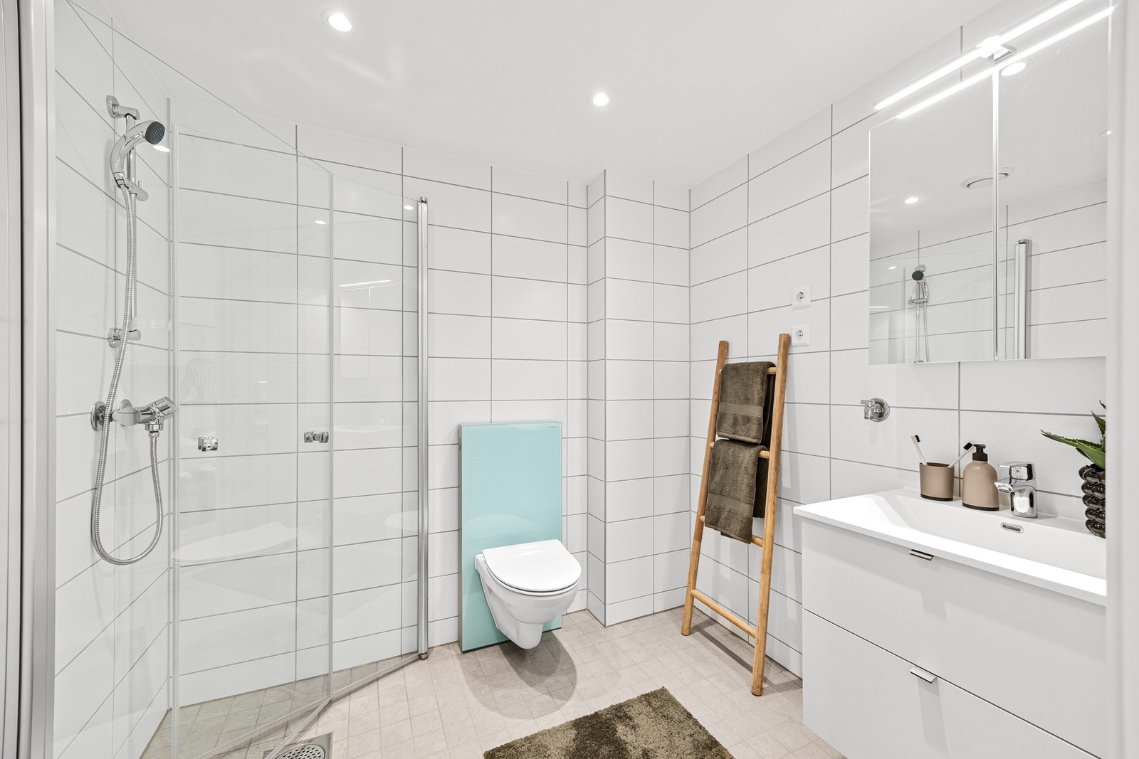 Pent baderom fra byggeår med varmekabler. Dusjhjørne, vegghengt toalett og opplegg til vaskemaskin. Galleribilde