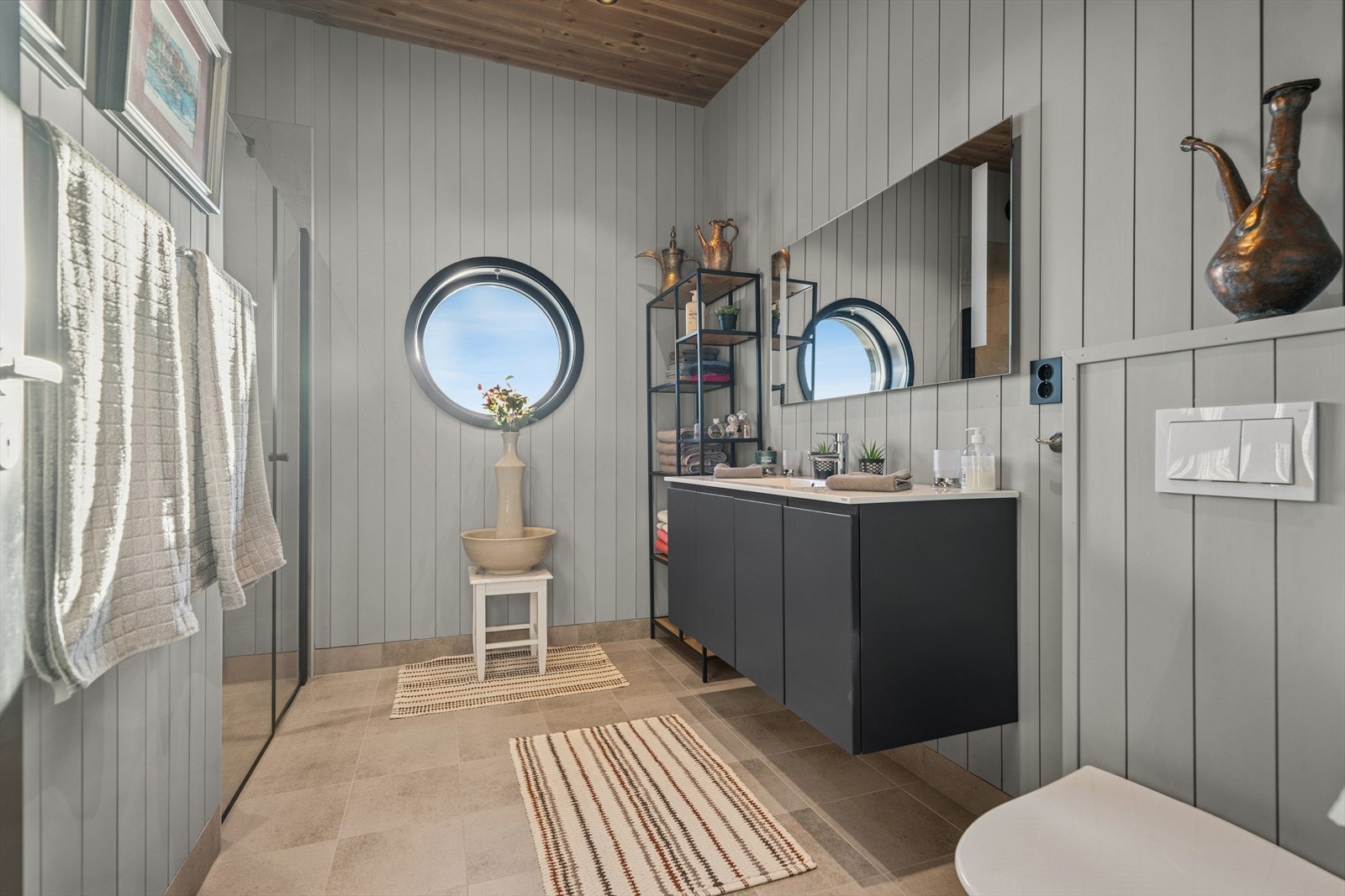 Badet er innredet med en praktisk baderomsinnredning med nedfelt servant, vegghengt toalett og dusjvegger som gir en effektiv og brukervennlig løsning. Galleribilde