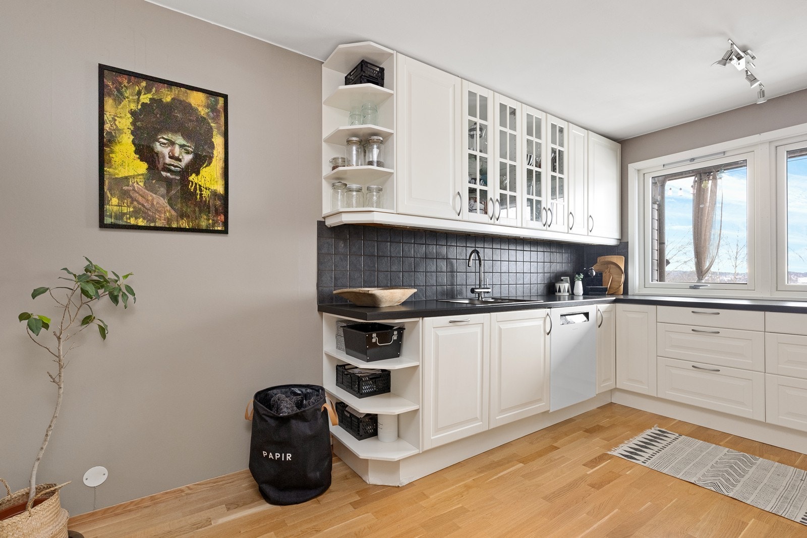 Kjøkkenet har profilerte, hvite fronter med overskap i glass og en benkeplate i laminat. Galleribilde