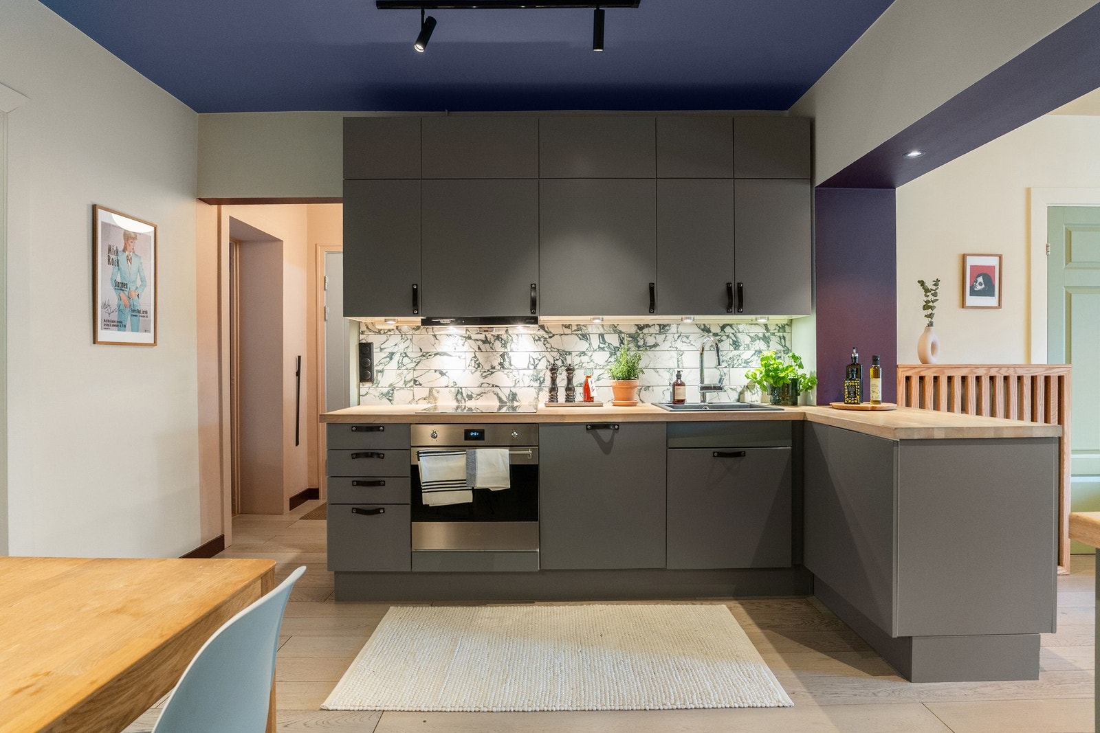 Kjøkkeninnredning med slette fronter, overskap med benkebelysning og fliser på vegger Galleribilde