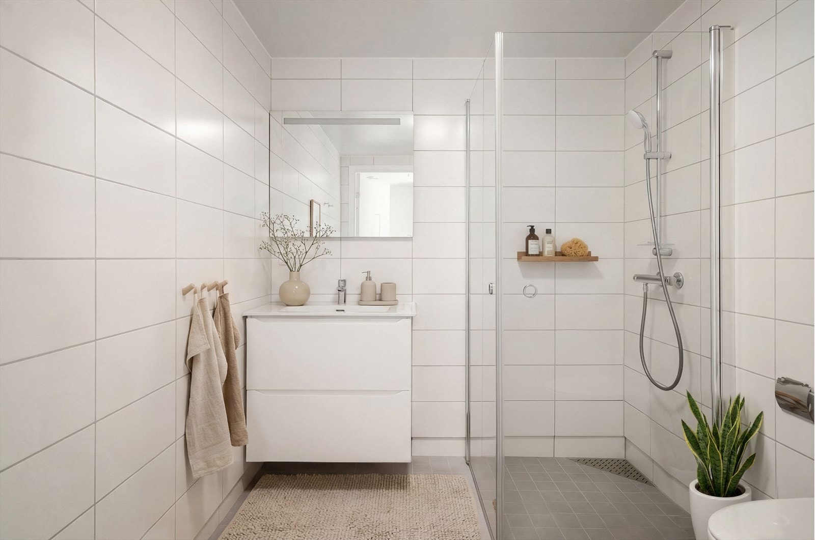 Illustrasjonsbilde - Baderommet fremstår lyst og innbydende, og er utstyrt med servantinnredning, praktisk dusjhjørne med innfellbare dusjdører og vegghengt toalett. Galleribilde