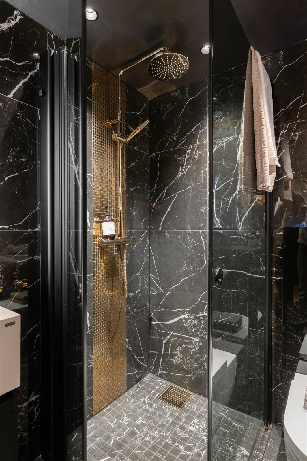 Dusjnisje med messing armatur og gullfargede mosaikkfliser. Galleribilde