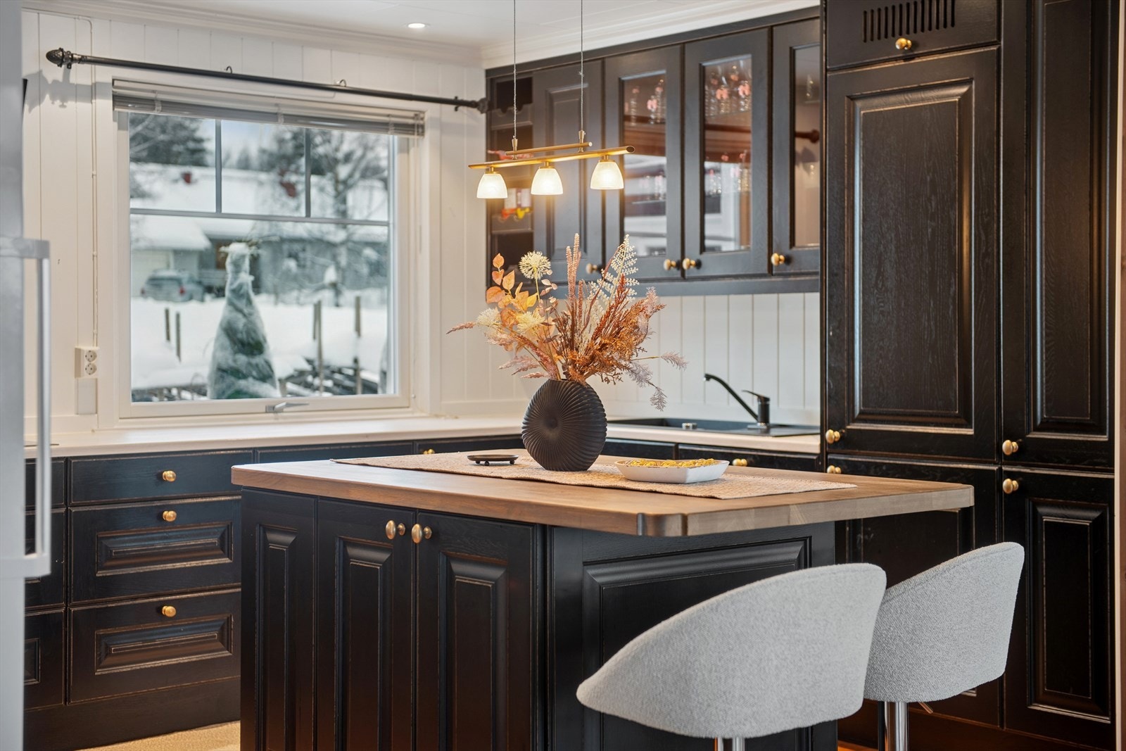 Kjøkkenet har en moderne innredning i heltre med profilerte fronter, laminert benkeplate og en praktisk kjøkkenøy med benkeplate i heltre. Galleribilde