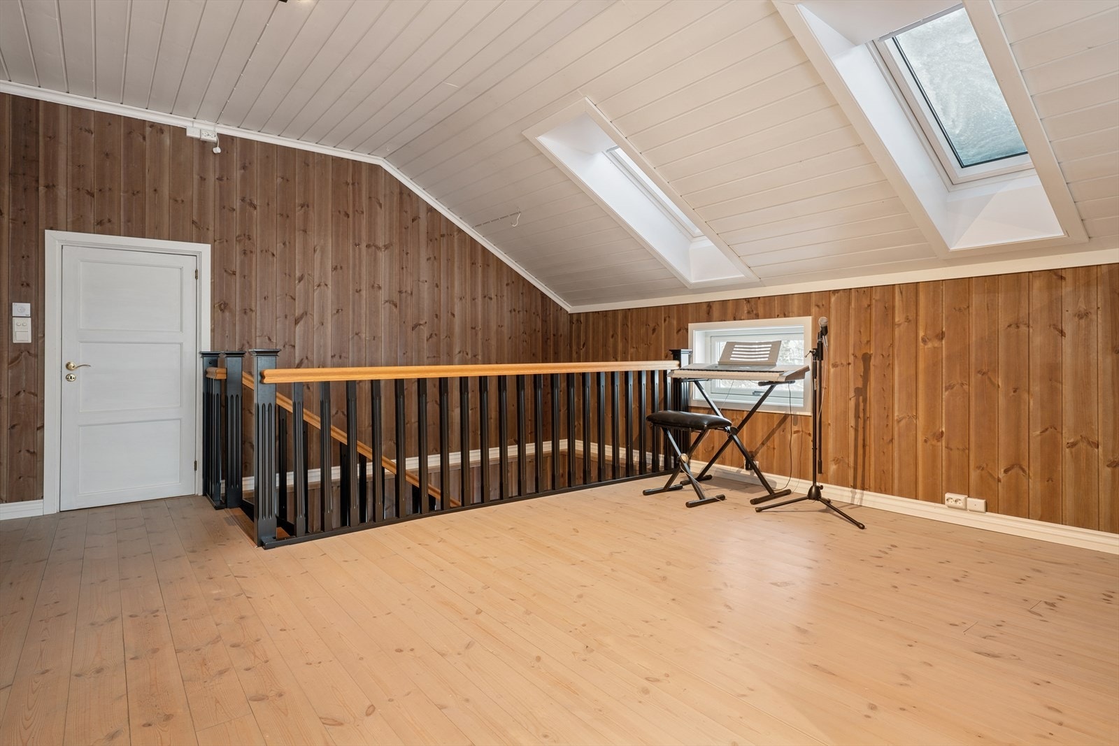 En trapp med åpne eiketrinn fører opp til en lys og trivelig loftstue. Galleribilde