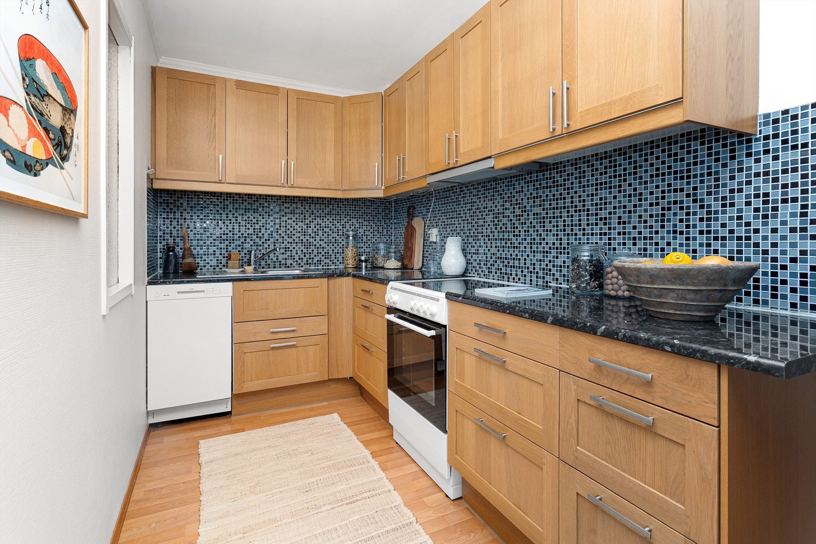 Separat og funksjonelt kjøkken med innredning med profilerte fronter, laminatbenkeplate med nedfelt vaskekum og fliser over benkeplaten. Galleribilde