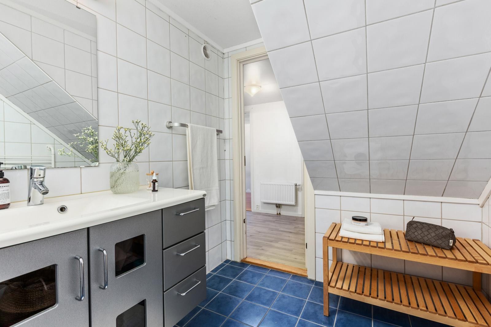 Bad med skråtak, flislagte vegger og gulv. Praktisk innredning med god oppbevaringsplass og stor speilflate. Galleribilde