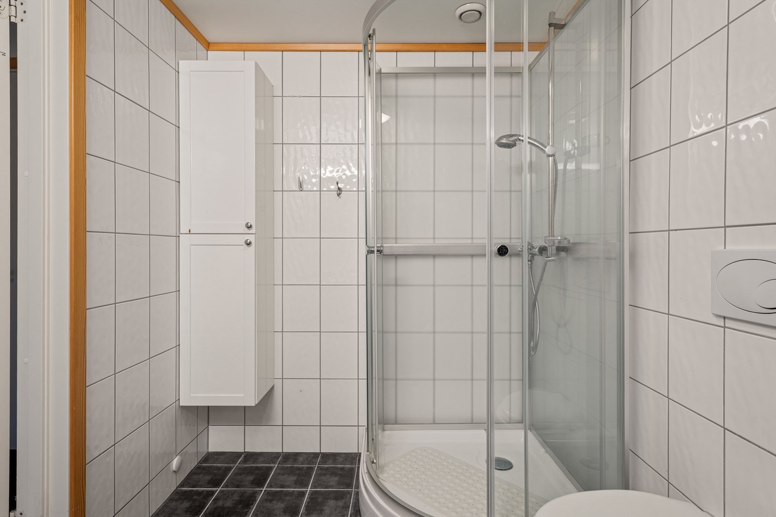 Videre er det montert dusjkabinett, vegghengt toalett og opplegg for vaskemaskin. Rommet har elektriske varmekabler i gulvet og lyspunkt i himlingen. Badet ventileres via ventil som er tilkoblet mekanisk avtrekk. Galleribilde