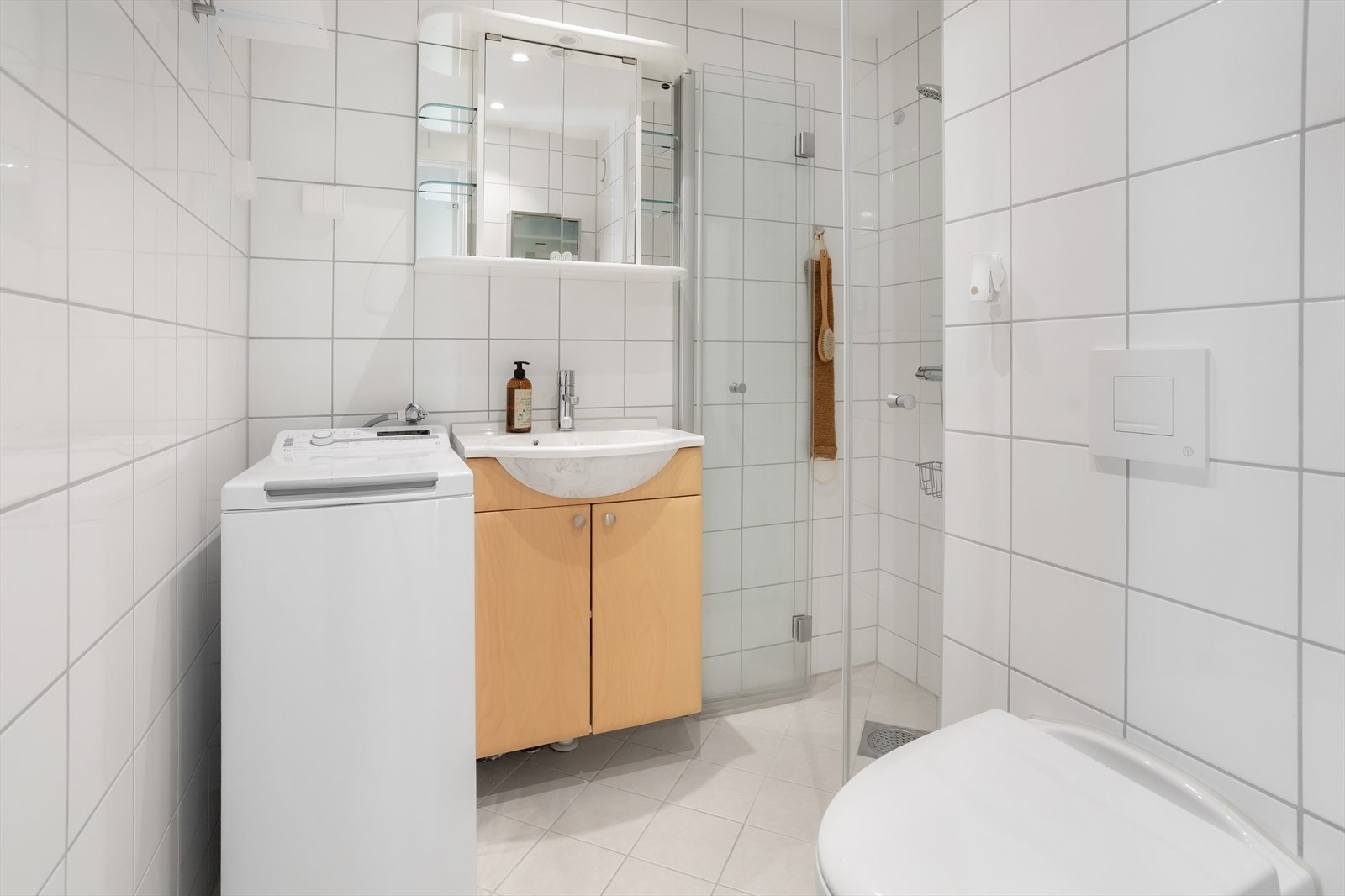 Helfliset baderom med vegghengt wc, servant med lagringsplass, dusjnisje og toppmatet vaskemaskin som følger med i handelen (Det er felles vaskeri i bygge til storklesvasken) Galleribilde