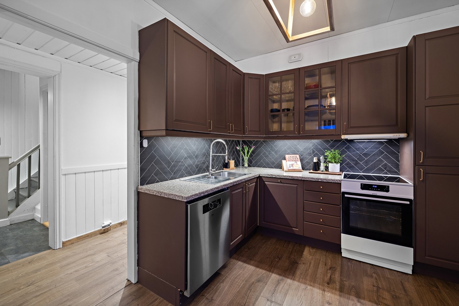 Innredningen har laminatbenkeplate og et dobbeltoverskap med glassdører. Galleribilde