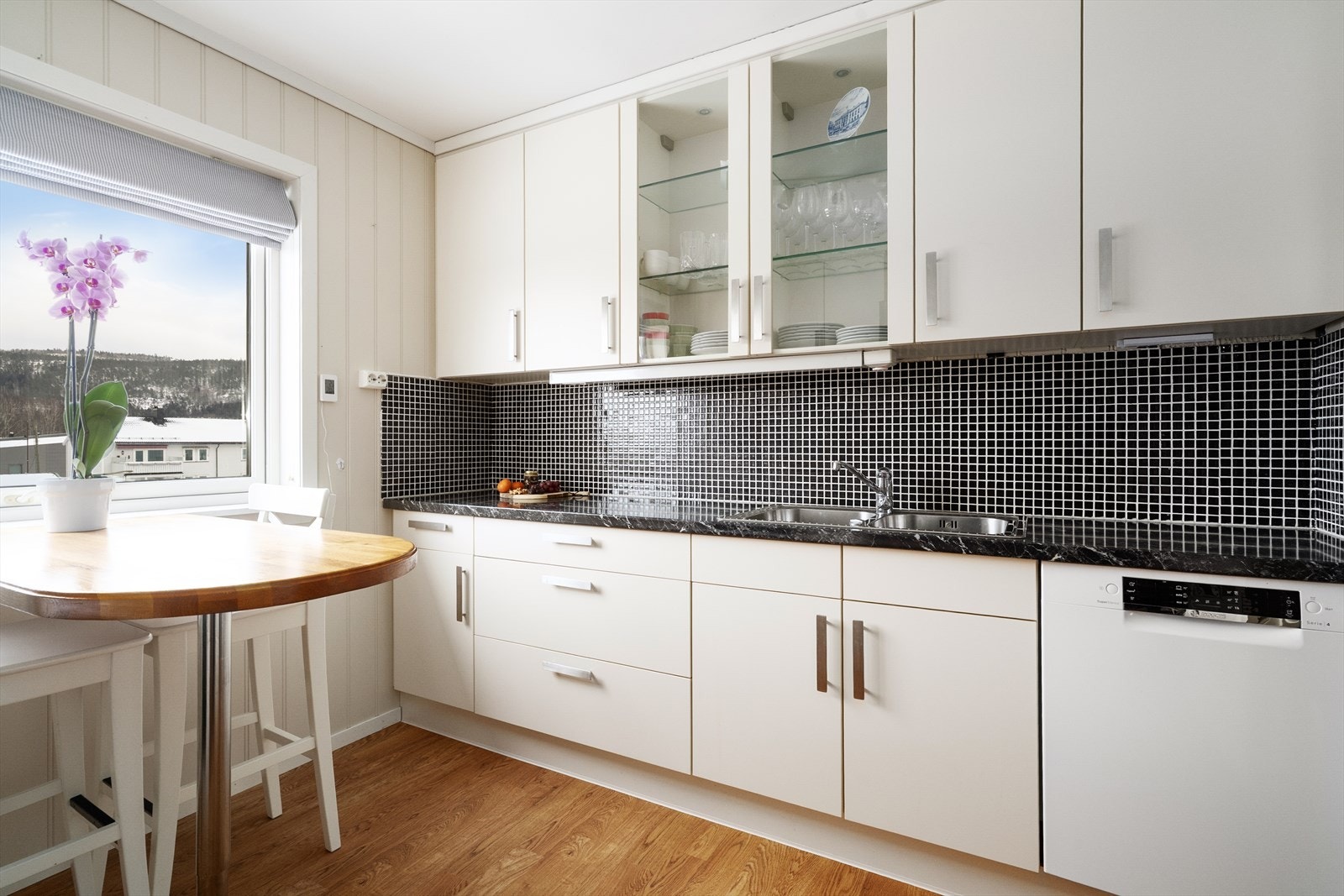 Mosaikkflis på vegg over laminat benkeplate med gode arbeidsflater. Nedfelt, dobbel oppvaskkum i rustfritt stål med ett-greps blandebatteri. Galleribilde