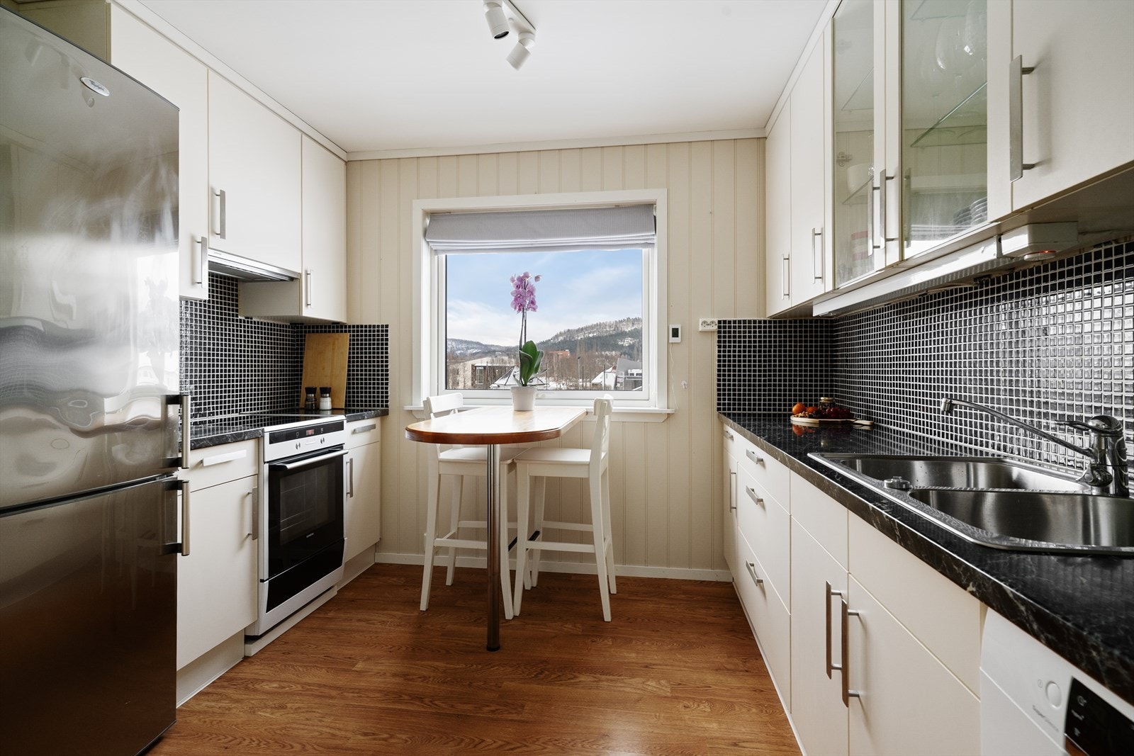 Lyst og romslig kjøkken med hyggelig spiseplass ved vindu og takhøy kjøkkeninnredning fra Bauformat. Innredningen har tidløse, glatte fronter. Galleribilde