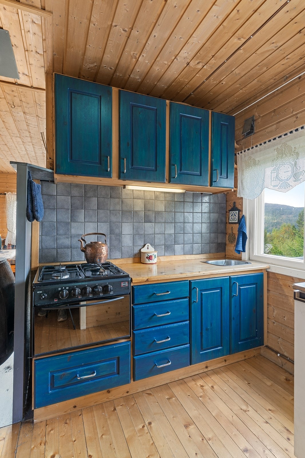 Malt innredning og benkeplate er av heltre. Det er avsatt plass til liten komfyr og kjøleskap. Galleribilde