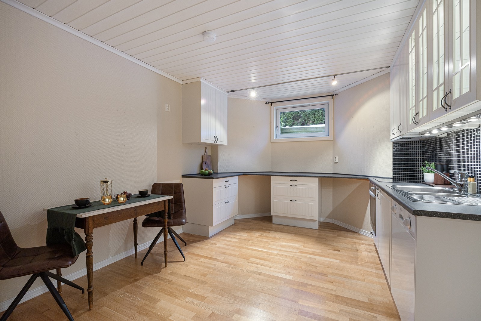 I kjelleren har boligen et kjøkken med spiseplass. Innredningen er fra Ikea med hvite, profilerte fronter, vitrineskap, benkeplate av laminat og dobbel oppvaskkum i stål. Oppvaskmaskin medfølger Galleribilde