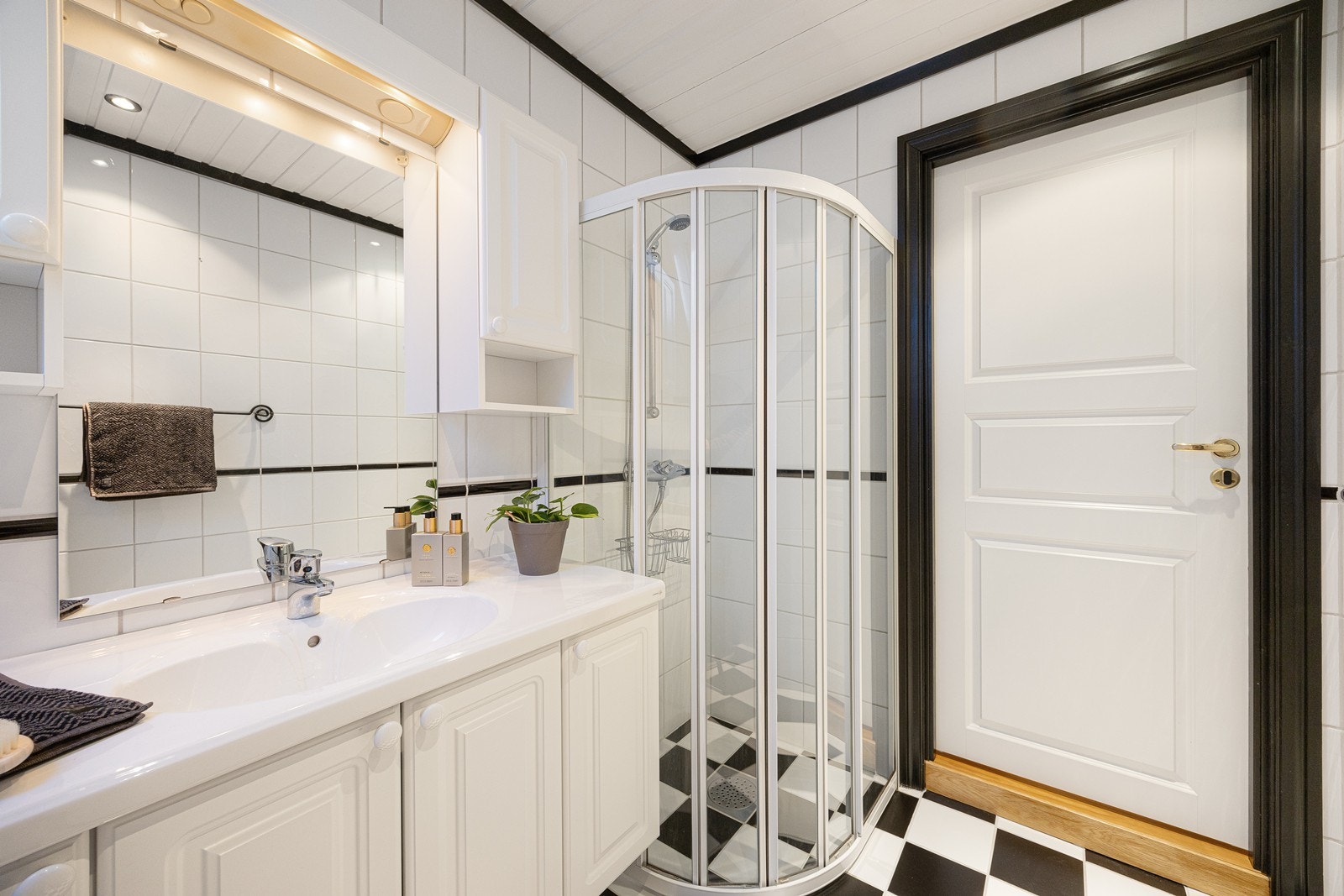 Baderomsinnredningen består av heldekkende servant med hvite underskap, veggskap i samme stil og et speil med tilhørende lys Galleribilde