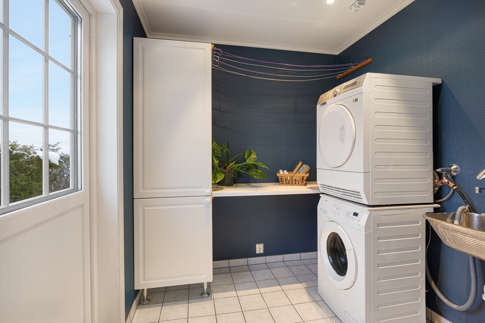 Vaskerommet har egen praktisk utgang. Rommet har downlights, utslagsvask, flislagt gulv med varme og et høyskap med tilhørende tørkebenk Galleribilde