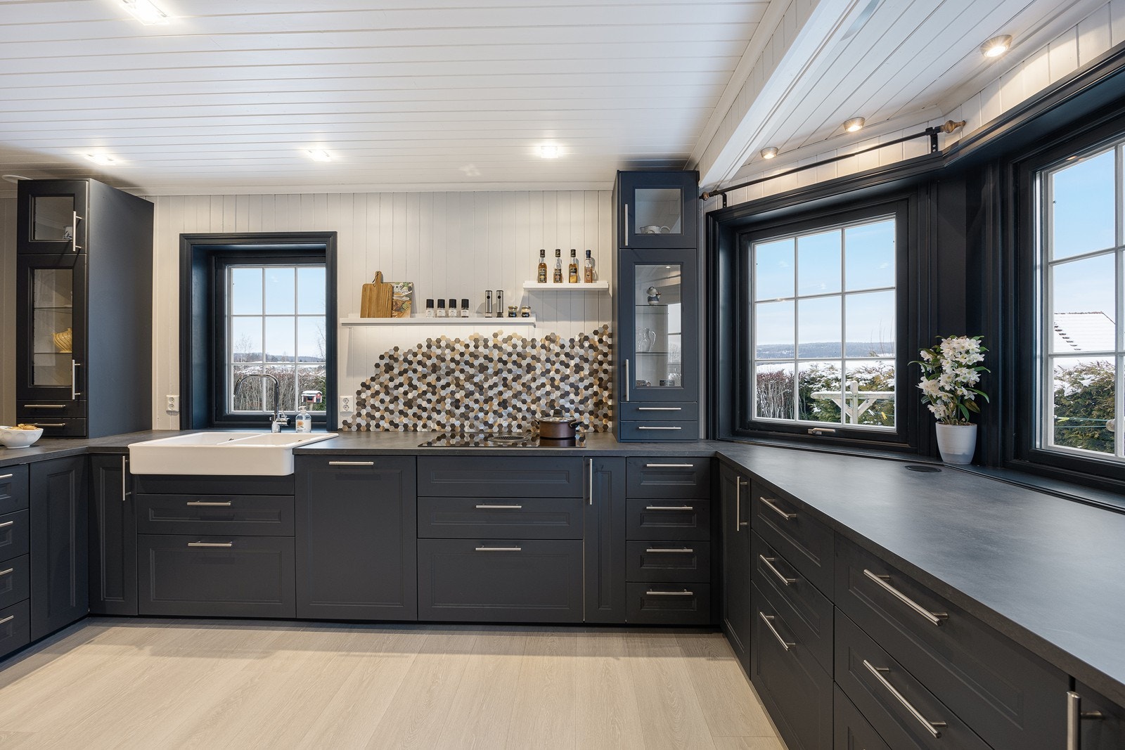 Ikea-innredningen er fra 2022, med mørke, profilerte fronter, store vitrineskap, benkeplate av laminat og dobbel oppvaskkum i porselen. Det er pop up-stikk i benkeplaten ved karnappen. Galleribilde