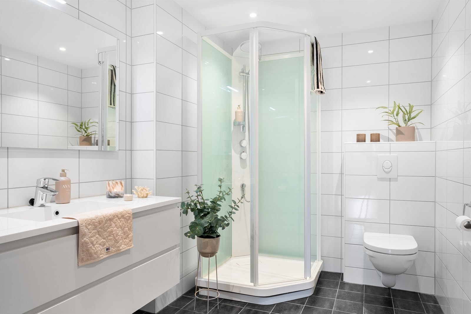 Badet er innredet med dusjkabinett, seksjon med heldekkende vask og veggmontert toalett. Galleribilde