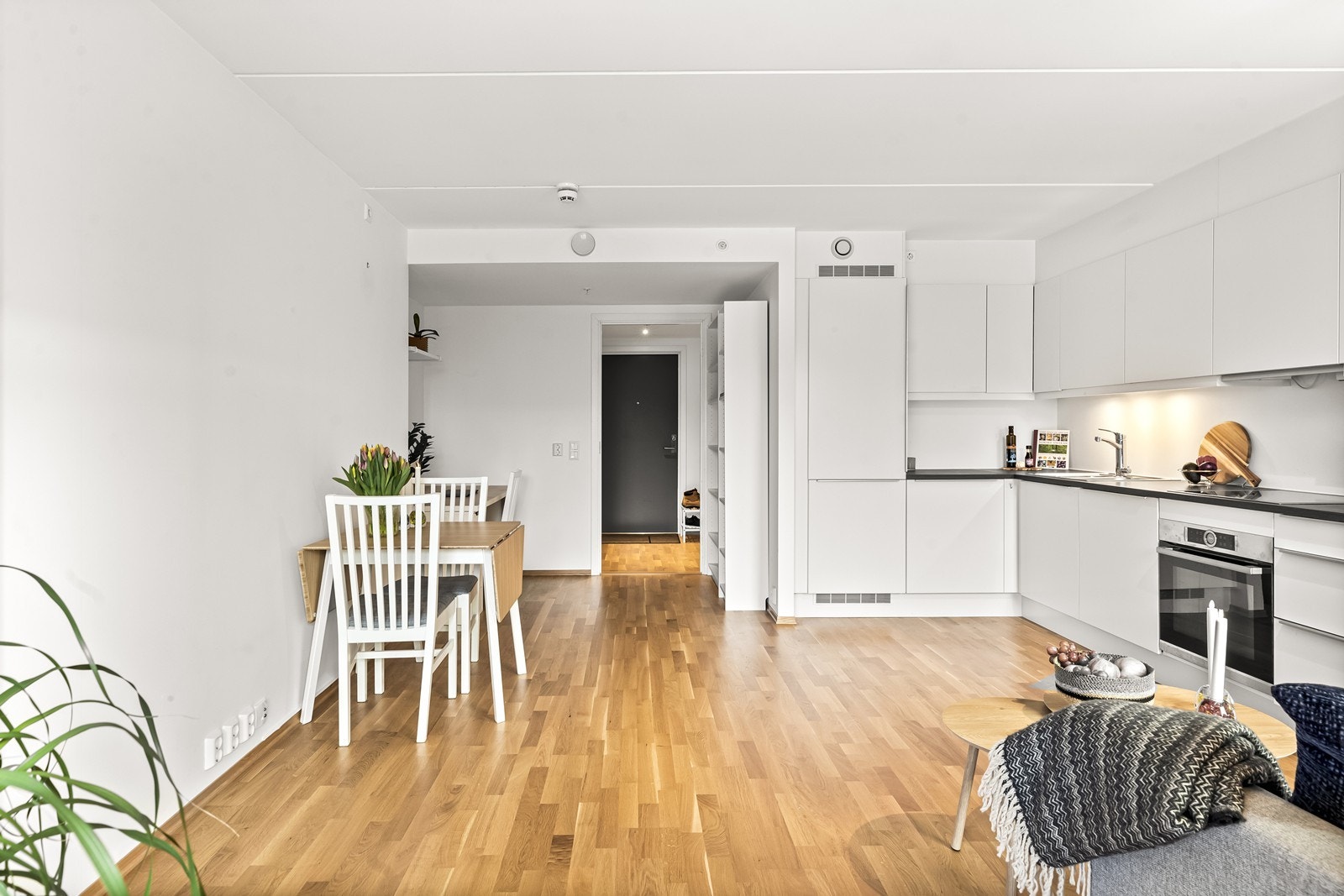 Kjøkkenet er hvitt med slette fronter, laminat benkeplate og belysning under overskap. Galleribilde