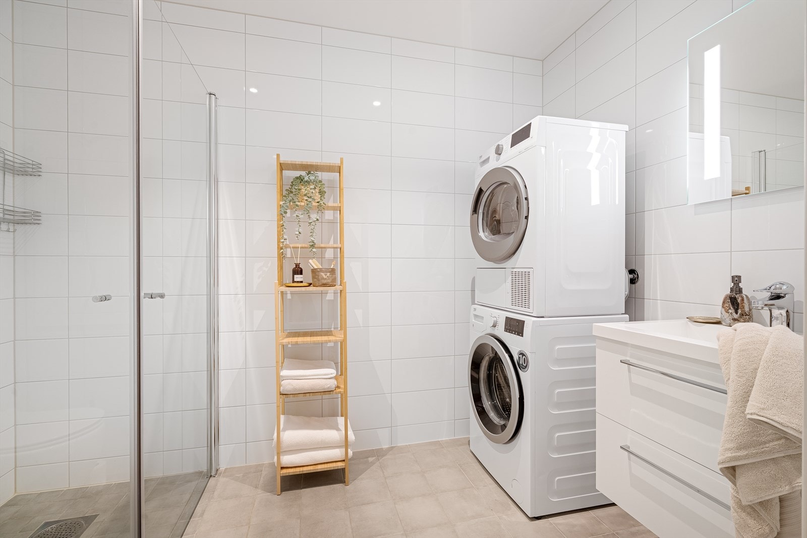 Badet er lekkert, helfliset og innredet med servant, vegghengt toalett med skjult sisterne, dusj med glassdører og opplegg for vaskemaskin. Galleribilde