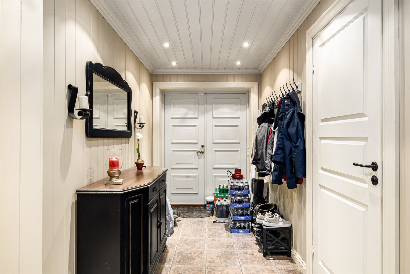 Velkommen inn i en romslig entré med flislagt gulv og doble inngangsdører. Galleribilde