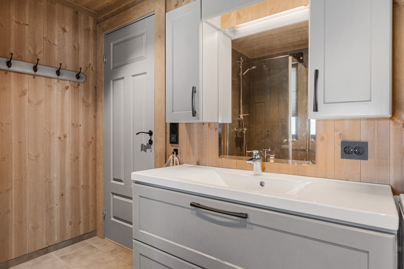 Badet er innredet med servantinnredning, vegghengt toalett, dusj med glassdør og opplegg til vaskemaskin. Galleribilde