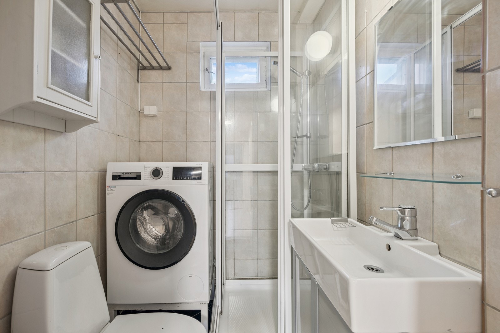 Bad med dusjkabinett, servant, toalett og vaskemaskin. Galleribilde