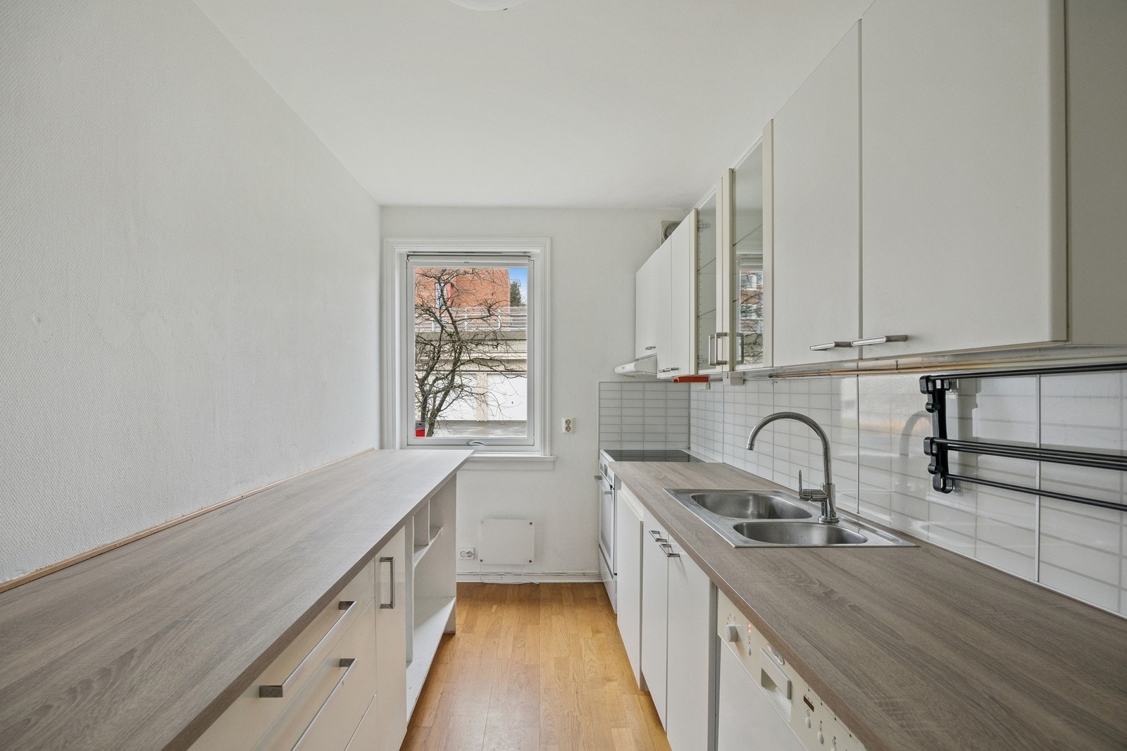 Lyst kjøkken med hvite glatte fronter og hvitevarer. Her er det godt med benkeplass. Galleribilde