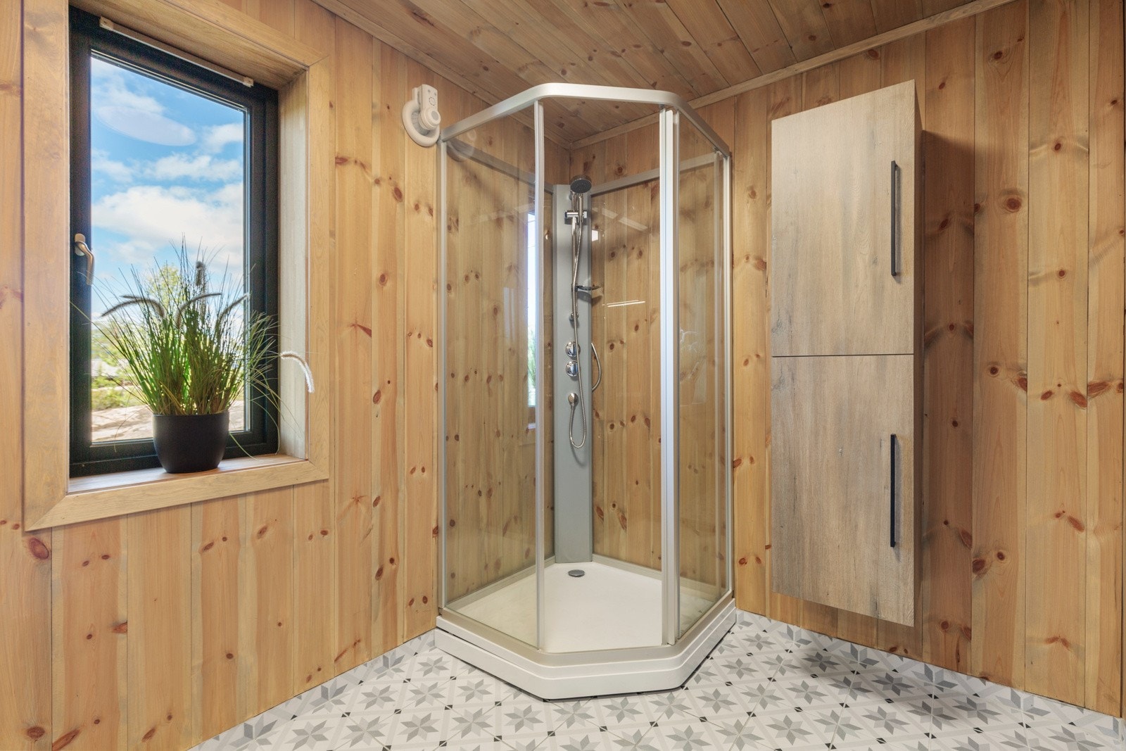 Hovedbadet i første etasje har fine fliser på gulvet og er innredet med benkeskap med nedfelt vask, veggmontert toalett og dusjkabinett. Galleribilde