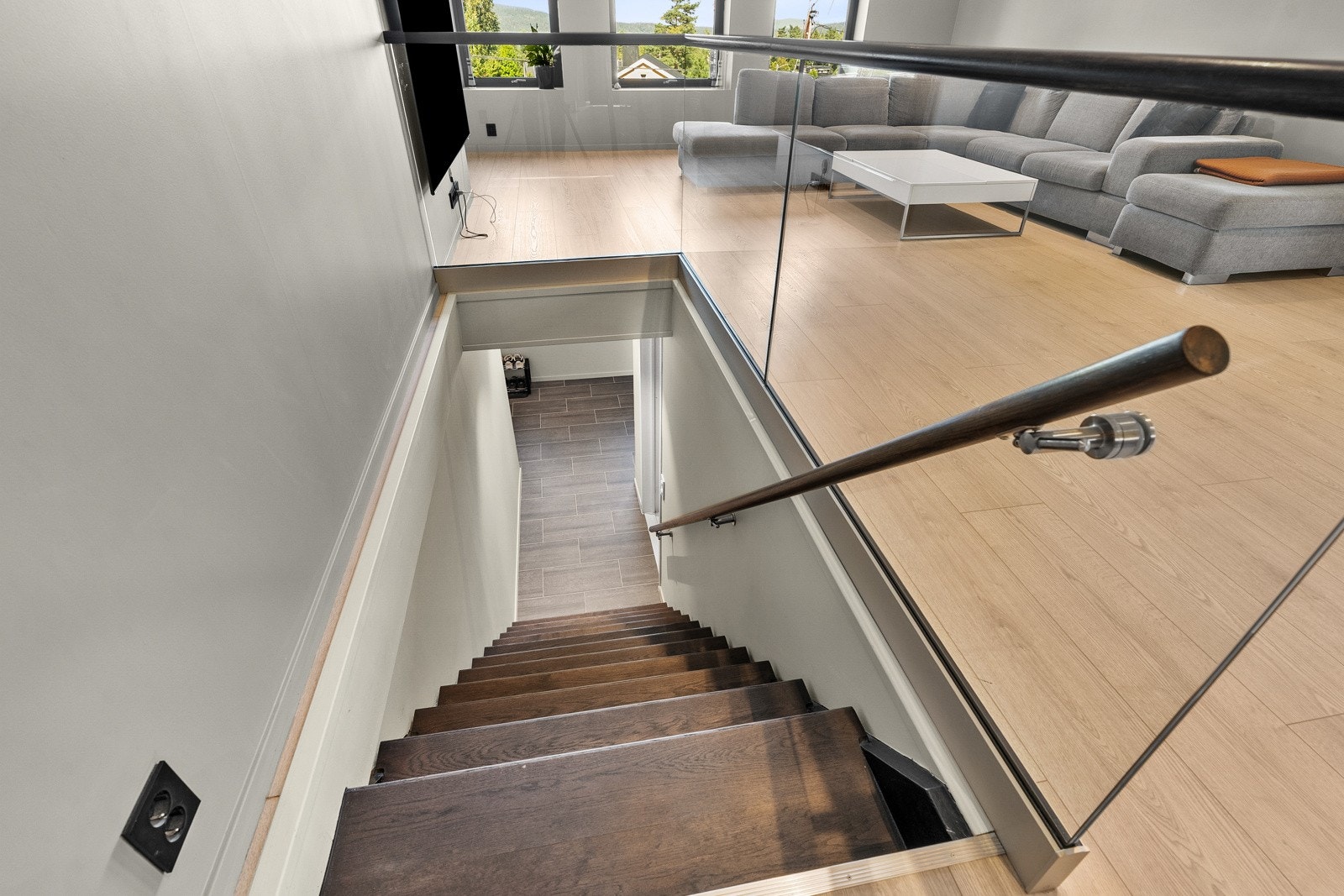 Stilren trappeløsning med glassrekkverk som skaper en åpen og moderne overgang mellom etasjene. Galleribilde