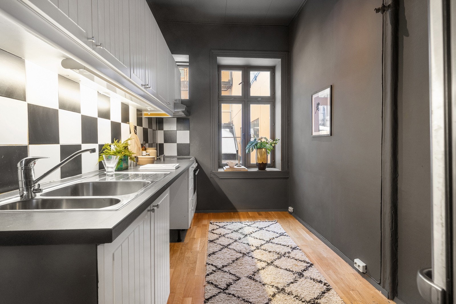 Kjøkkenet har en funksjonell utforming med innredning langs én vegg. Innredningen har profilerte, malte fronter og laminat benkeplate. Kjøkkenet har vindu som gir dagslys og naturlig lufting. Galleribilde