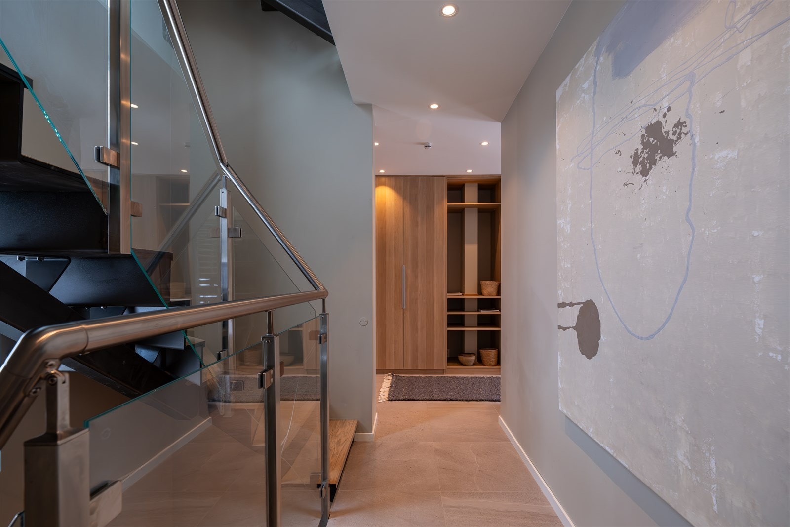 Praktisk flislagt entré/gang.Trappen er en plassbygd ståltrapp med eike-trinn og glassrekkverk. Spesialdesignet for huset Galleribilde