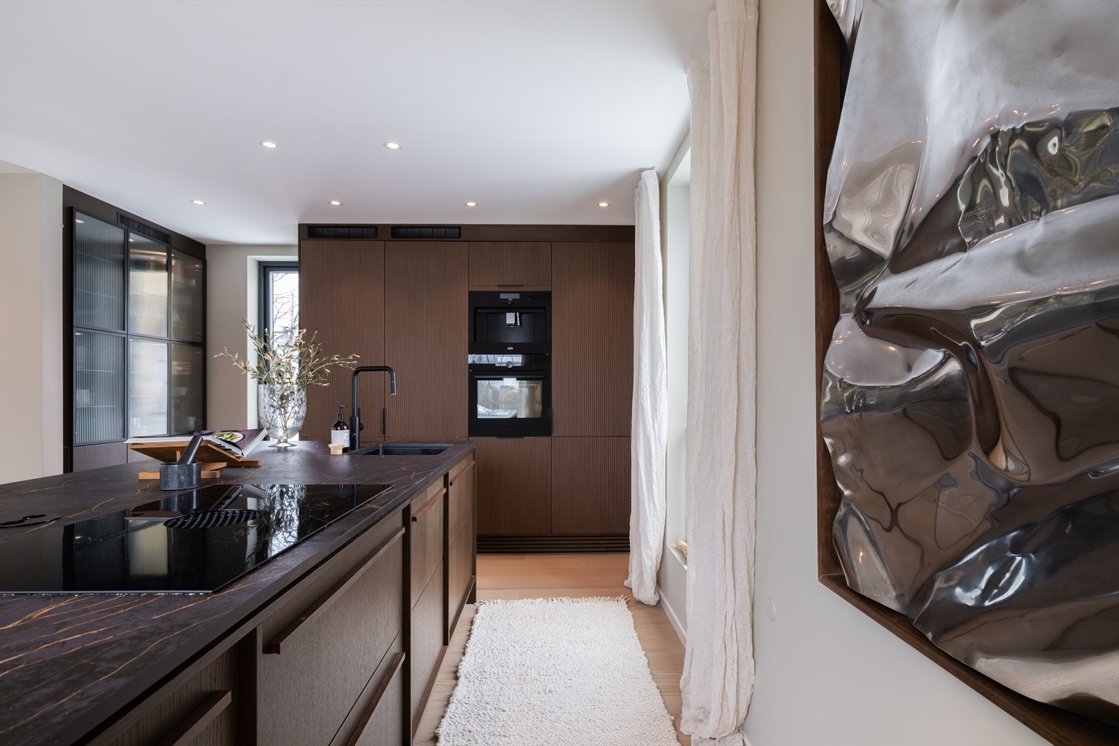 Kjøkkenet er innredet med integrerte hvitevarer bestående av induksjonstopp, stekeovn, oppvaskmaskin, kaffemaskin samt kjøl/frys Galleribilde