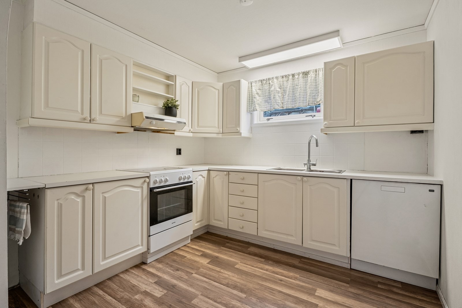 Innredning med profilerte fronter og en laminatbenkeplate med nedfelt kum i rustfritt stål. Opplegg for oppvaskmaskin. Galleribilde