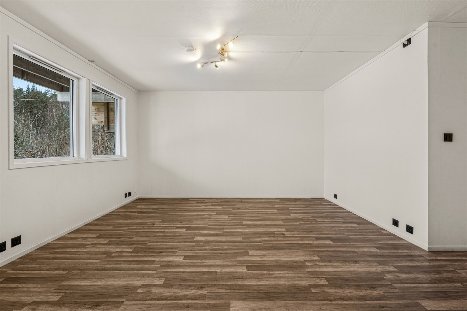 Romslig stue med praktisk laminatgulv og lysmalte vegger. Galleribilde