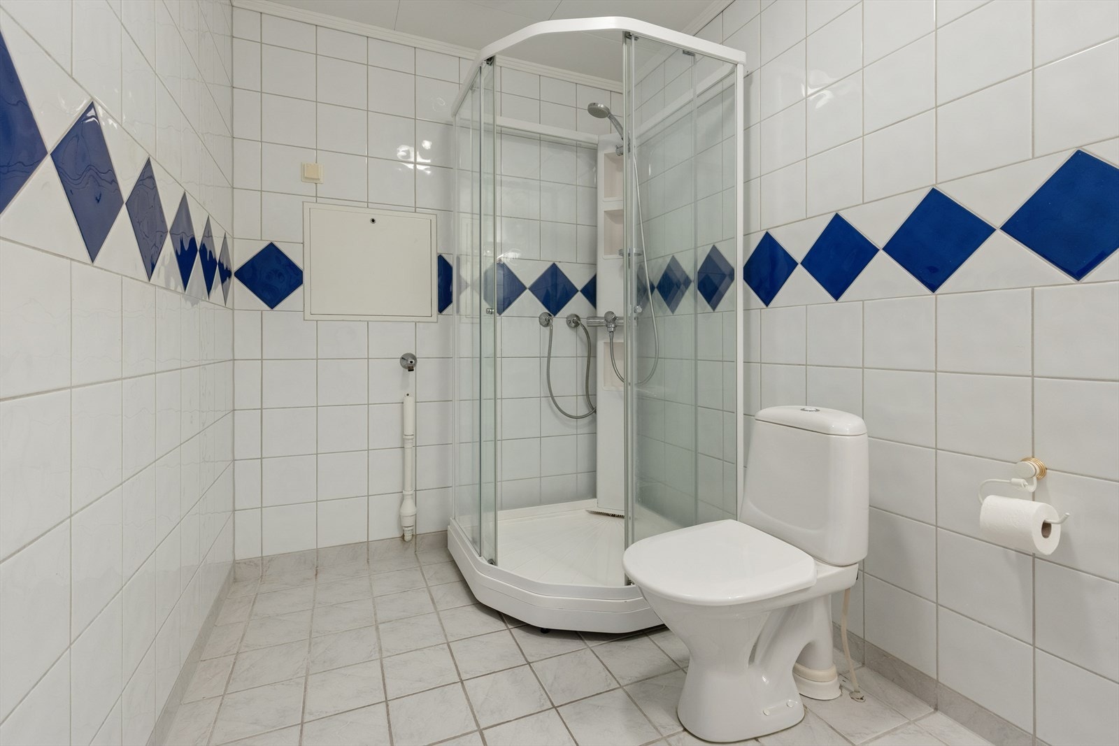 Flislagt bad med varmekabler i gulvet, vegghengt servant, speil og dusjkabinett. Galleribilde